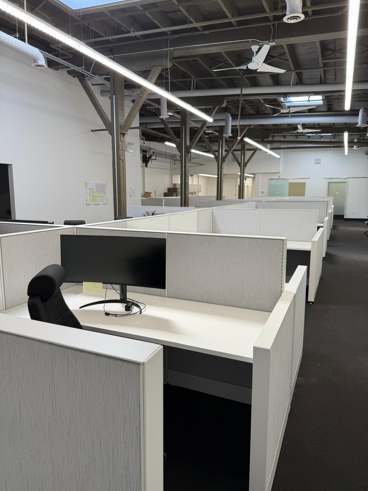 Open-plan office workstations beneath exposed ceiling beams at 1880 Assumption, Windsor