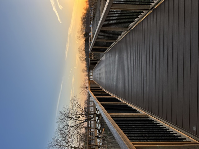 View along the completed Caldwell Marina Conservation Boardwalk, with railings on both sides at sunset